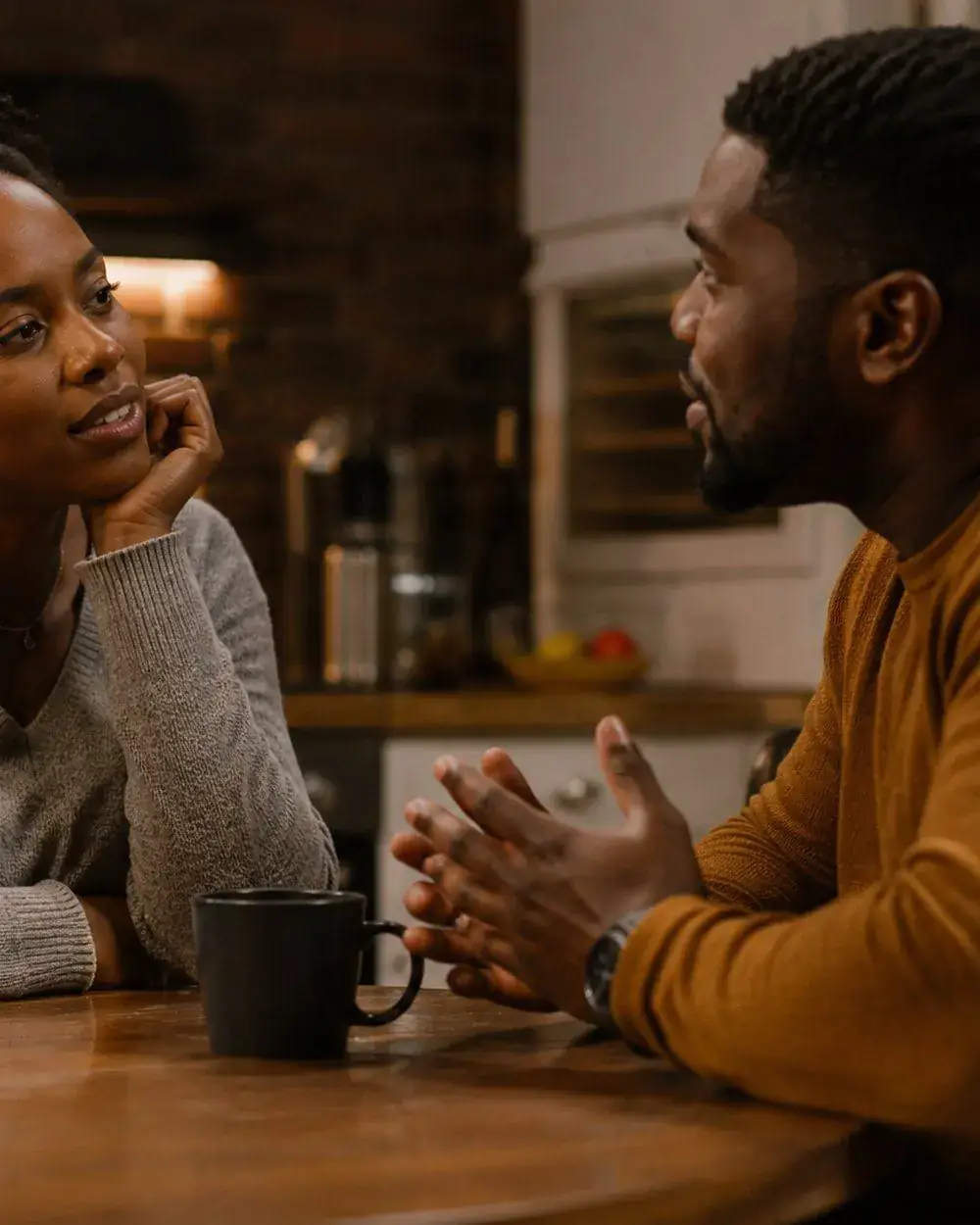 A couple talking across a kitchen table